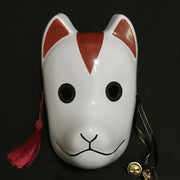 A white Kitsune mask with red marking with black eyes, a black nose, and a red tassel hanging from the side.